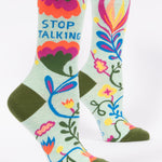 Colorful socks with floral designs and text on a light green background. Available at Be Charmed