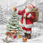 Santa Claus with a sack of gifts standing next to a decorated Christmas tree in a snowy village setting paper cocktail napkins. Available at Be Charmed.