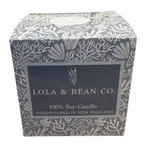 A 3-wick soy candle by Lola & Bean in a boxed container with a floral pattern. The label on the box indicates it is a 100% Soy Candle handpoured in New England. Available at Be Charmed