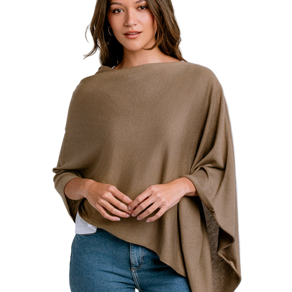 Woman wearing a brown poncho over a white shirt and blue jeans on a white background
