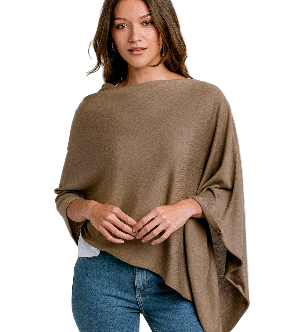 Woman wearing a brown poncho over a white shirt and blue jeans on a white background