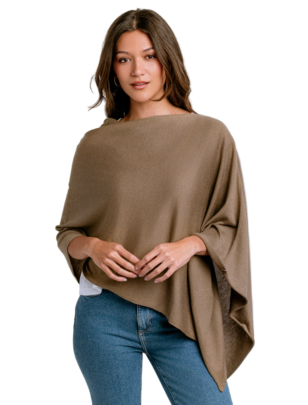 Woman wearing a brown poncho over a white shirt and blue jeans on a white background