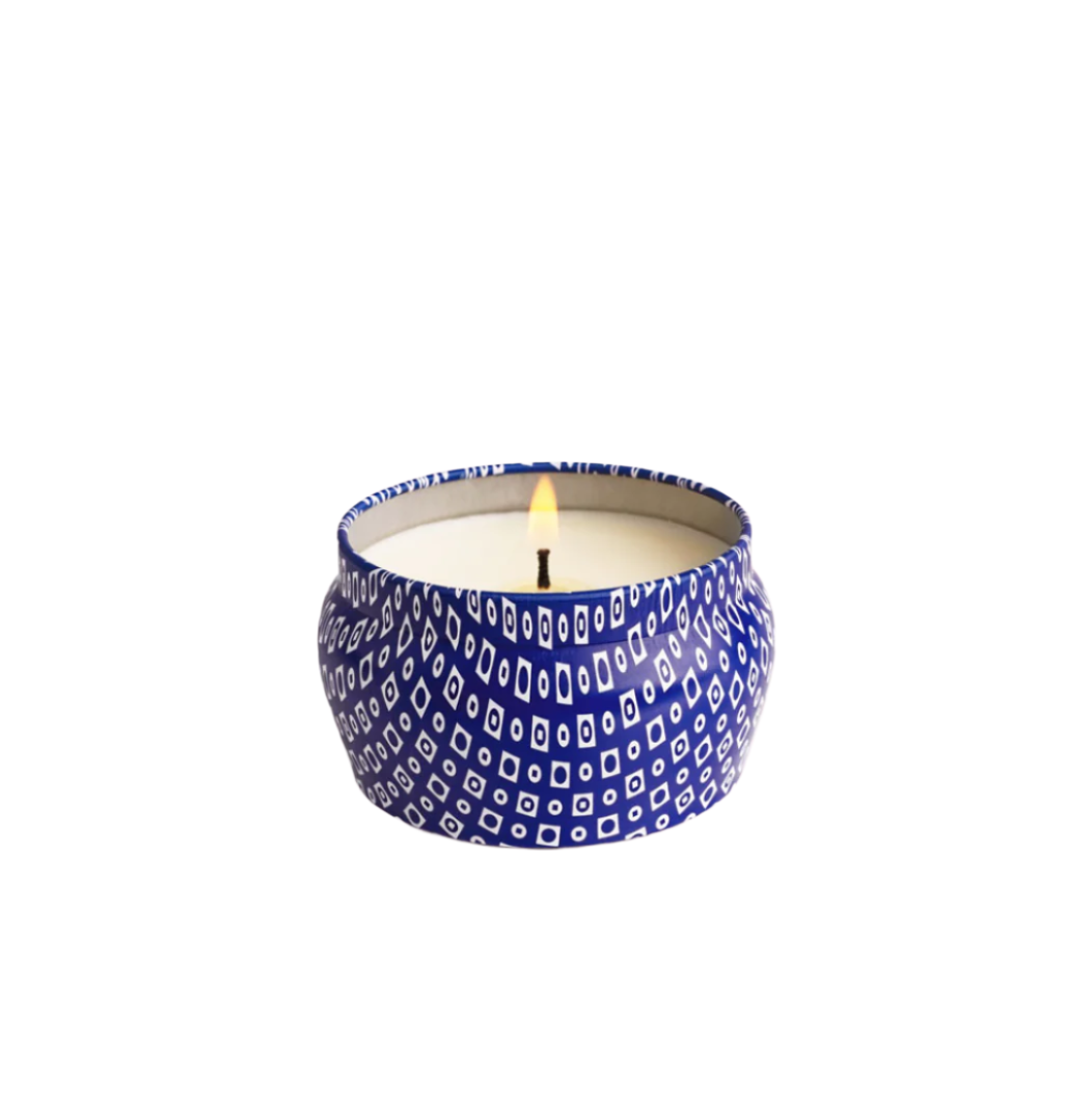 Opened & lit Capri Blue Volcano Blue Mini Tin Candle—3 oz cobalt-blue tin with tropical citrus and sugared pineapple scent, portable and stylish, available at Be Charmed.