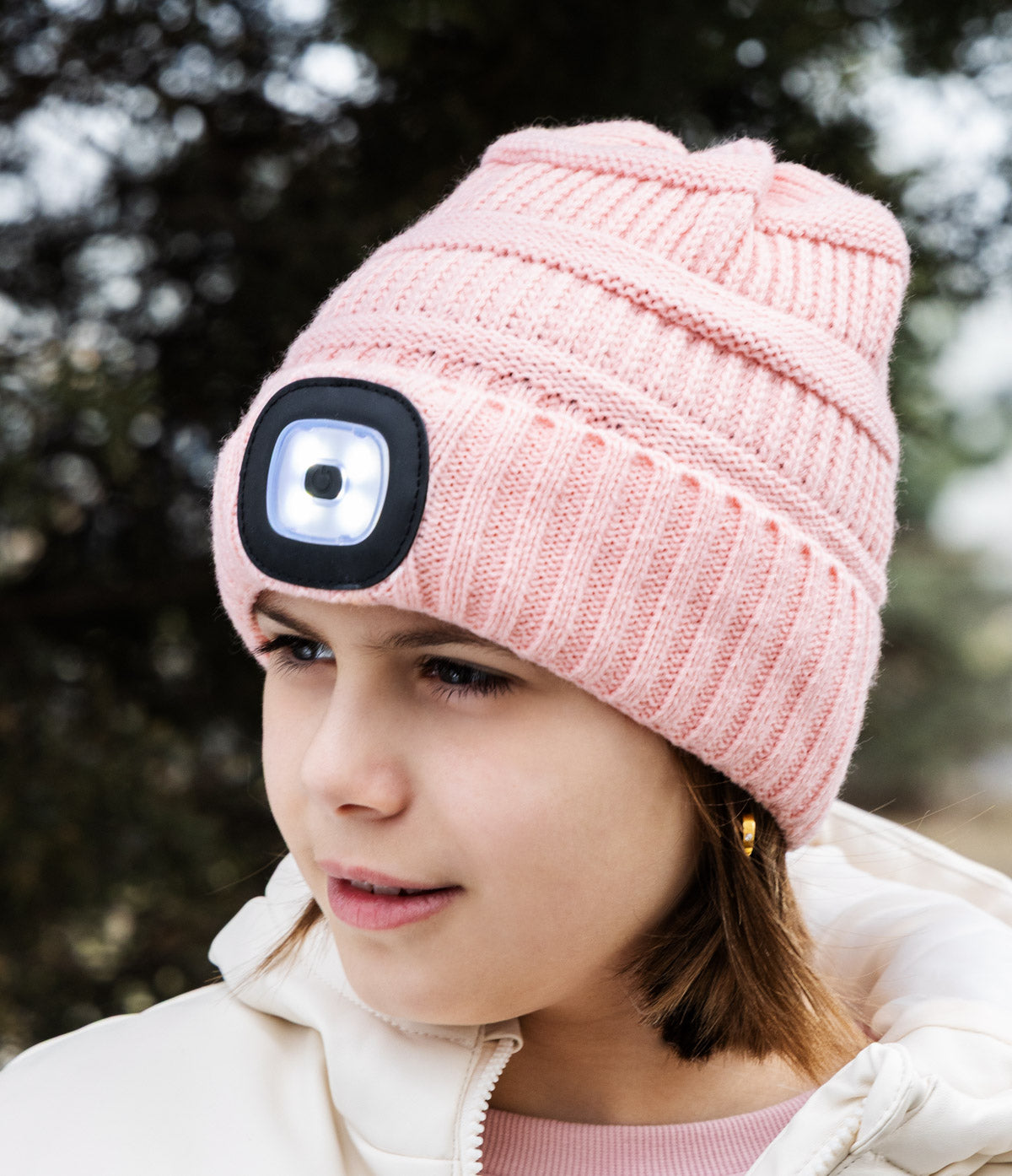 Pink knit beanie with a built-in light on a child outdoors. Available at Be Charmed