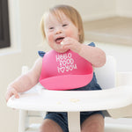 Child wearing a Bella Tunno "Hello Food I Love You" Wonder Bib in pink, featuring an adjustable neck and catch pocket, available at Be Charmed.