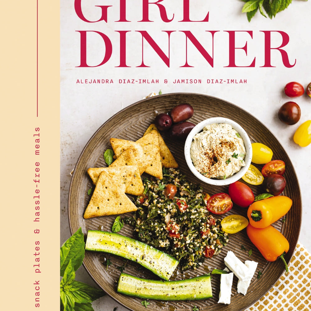 Book cover of 'Girl Dinner' with a plate of food and ingredients on a white background. Available at Be Charmed