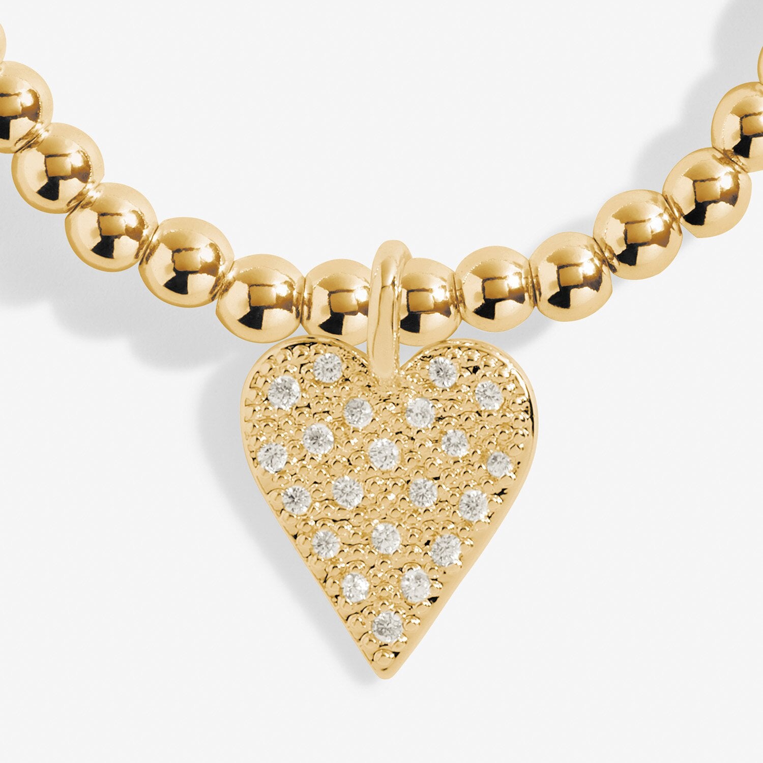 Gold necklace with a heart-shaped pendant featuring diamond-like stones on a white background. Available at Be Charmed