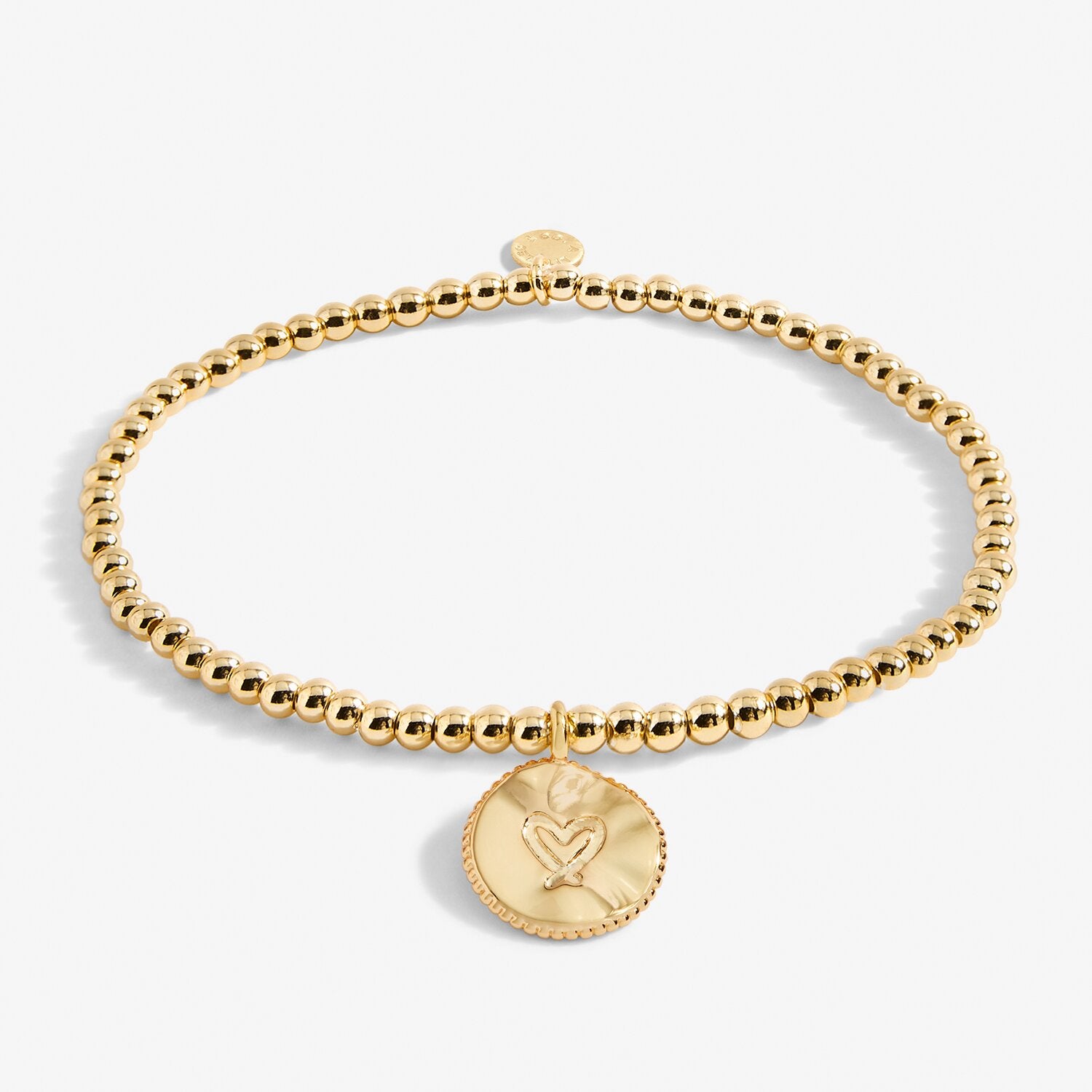 Gold beaded bracelet with a heart-shaped charm on a white background. Available at Be Charmed