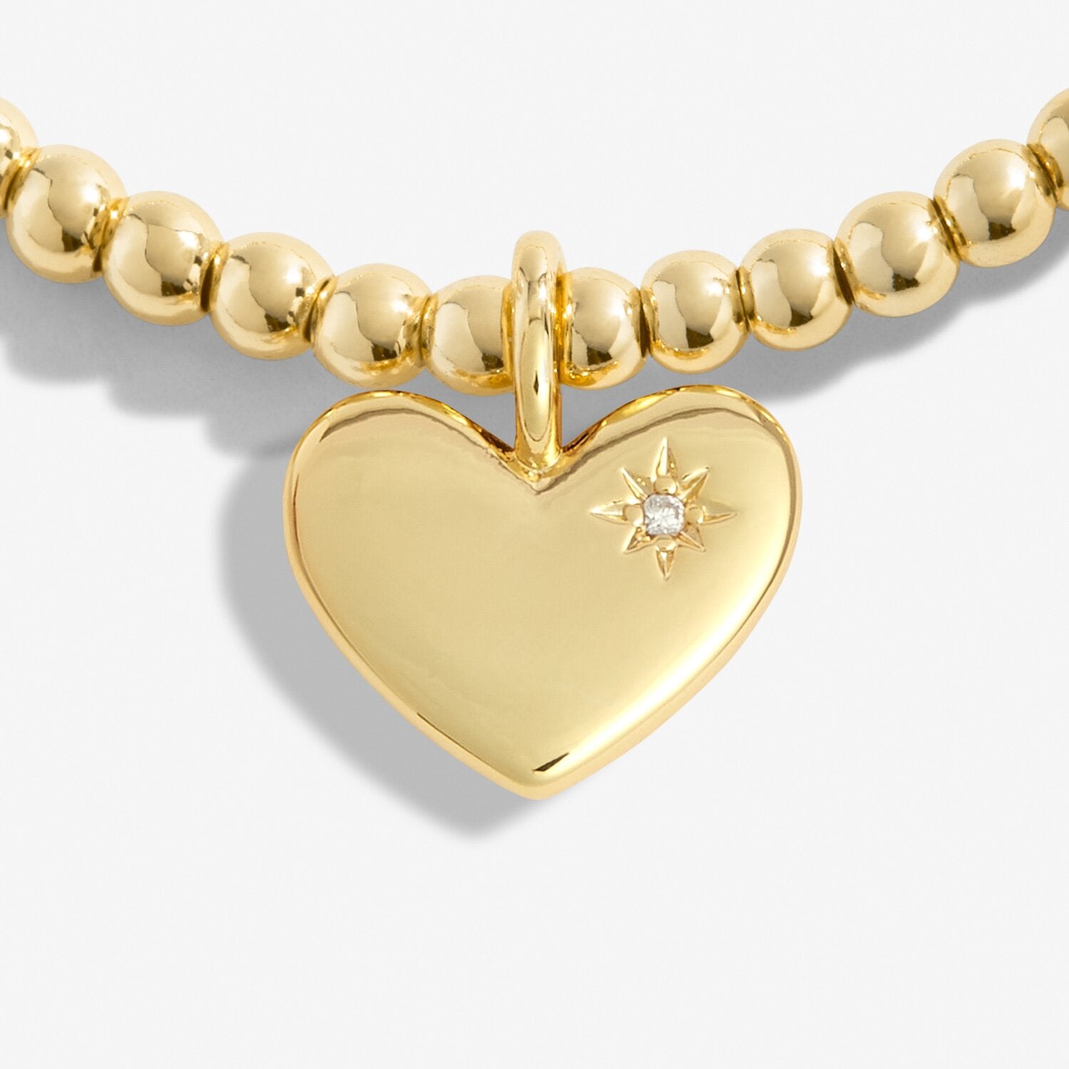 Gold beaded bracelet with a heart-shaped pendant featuring a diamond on a white background. Available at Be Charmed