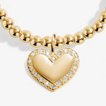 Gold necklace with a heart-shaped pendant on a white background. Available at Be Charmed