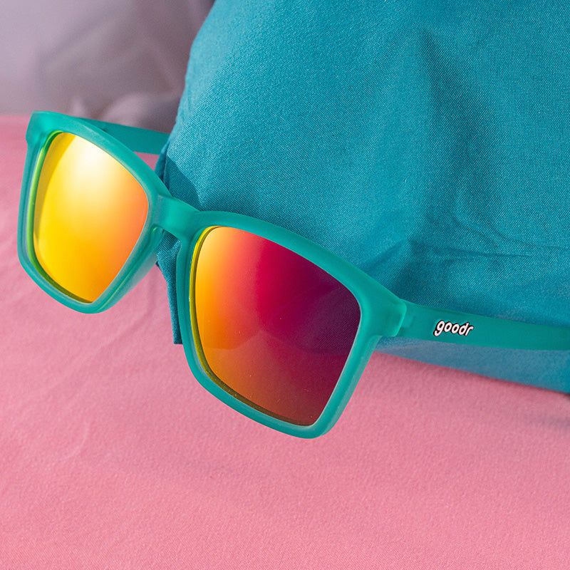 Close up view of Short With Benefits Goodr sunglasses with pink mirrored lenses and hot pink no-slip frames—polarized for active wear; available at Be Charmed