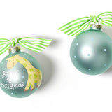 Two round glass ornaments with a Christmas theme. One has a green and white color scheme with a giraffe illustration and the text 'Baby's 1st Christmas'. Available at Be Charmed