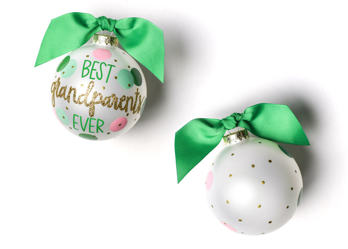 Two round glass ornaments with a green and pink polka dot design and gold glitter, finished with green ribbons. Available at Be Charmed