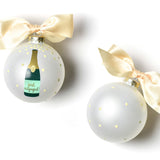 Two Christmas ornaments with champagne bottle design and gold bows on a white background. Available at Be Charmed