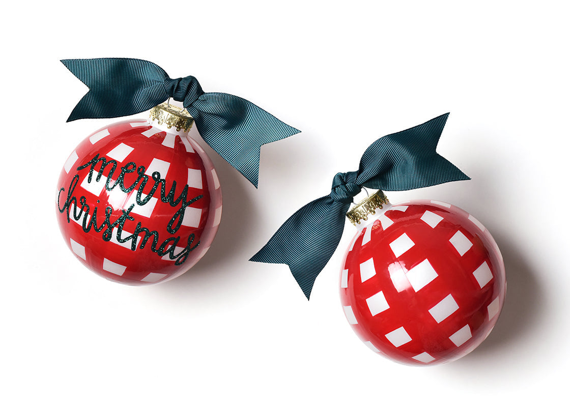 Coton Colors “Merry Christmas” glass ornament decorated with red and white gingham pattern, festive script, and gold glitter trim—Available at Be Charmed