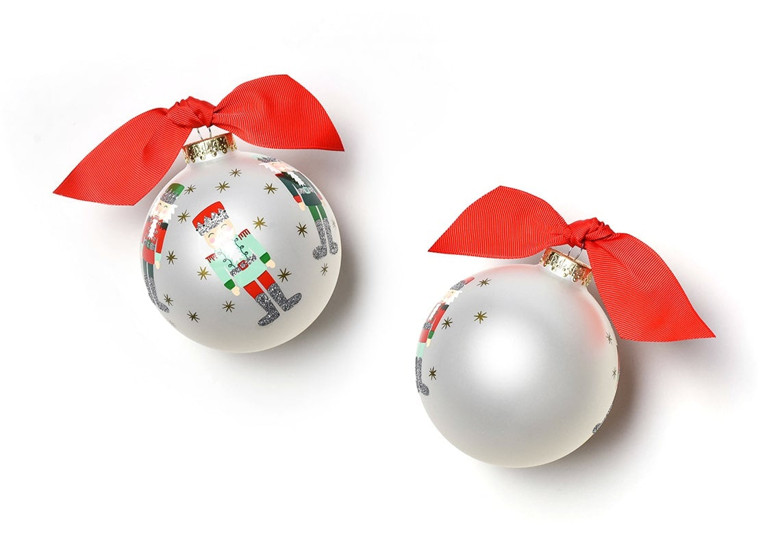 Coton Colors hand-painted Nutcracker glass ornament with festive gold-star accents, wrapped red ribbon topper, includes matching gift box—Available at Be Charmed