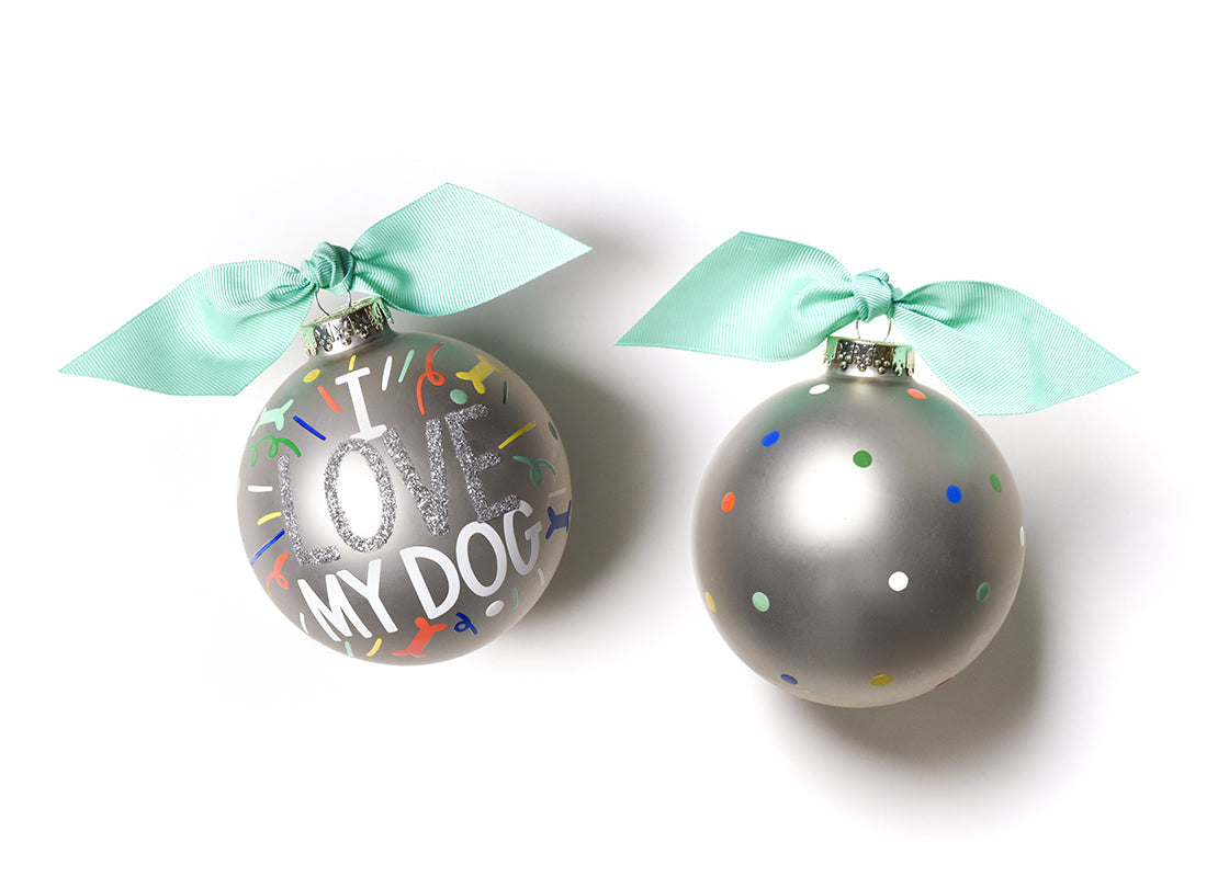 Coton Colors “I Love My Dog” oversized silver popper glass ornament with hand‑painted paw prints and silver glitter accent, includes swirled metal stand – Available at Be Charmed