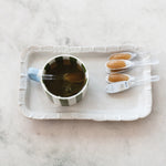 Cup of tea with honey on a white tray on a marble surface. Available at Be Charmed