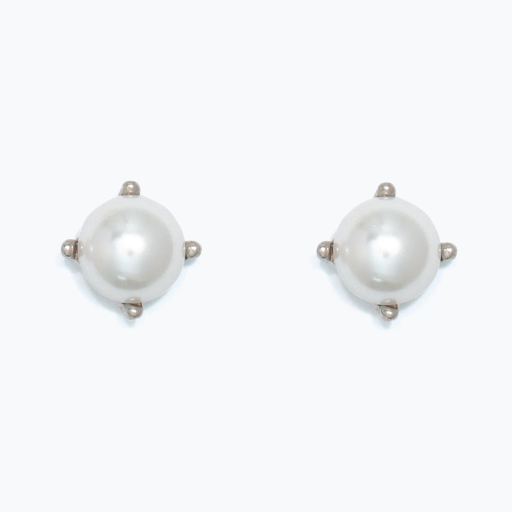 Pair of pearl earrings in silver setting on a white background. Available at Be Charmed