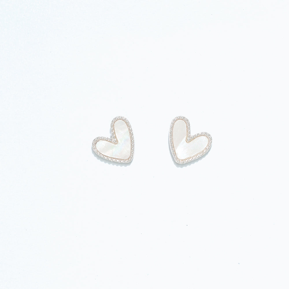 A pair of pearlized silver heart earrings on a white background. Available at Be Charmed