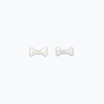 Cuties silver dog bone stud earrings featuring mini bone silhouette in polished silver-tone hypoallergenic metal with butterfly backs. Cute and lightweight accessory. Available at Be Charmed