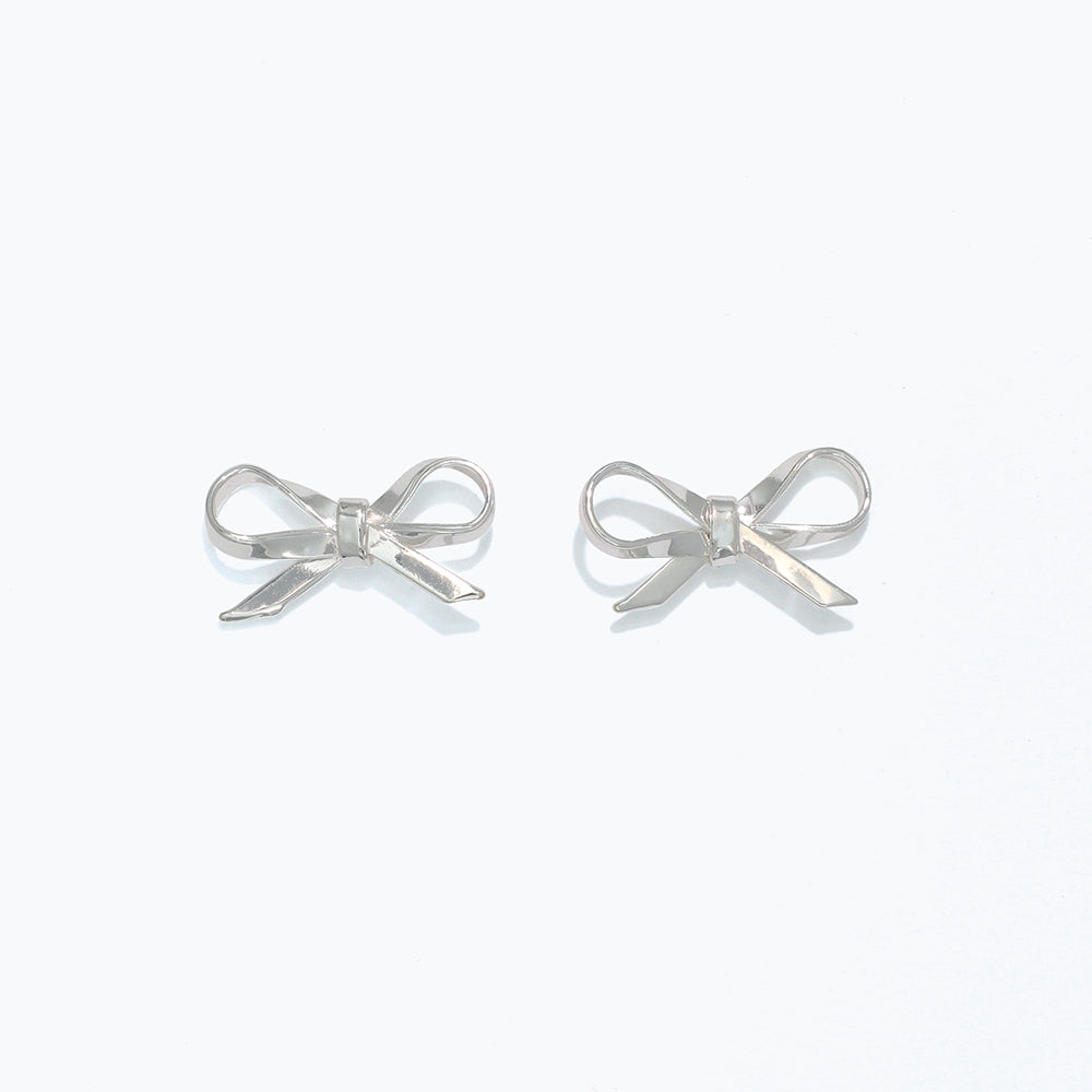 A pair of silver ribbon bow stud earrings on a white background. Available at Be Charmed