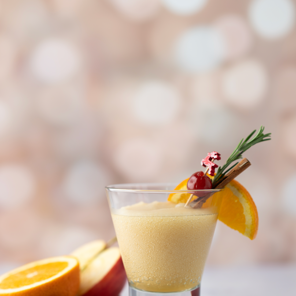 Glass of Blitzen Bourbon with garnishes on a blurred background. Available at Be Charmed.  