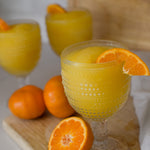 Picture of filled glass of D'marie Mimosa Slush Mix pouch with citrus design, a craft cocktail mix to combine with champagne and freeze. Refreshing and easy. Available at Be Charmed