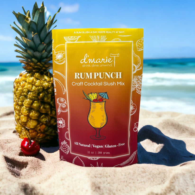 D'Marie Rum Punch Slush Mix pouch featuring tropical fruit graphics—craft cocktail mix to combine with rum and freeze. Bright, fruity, and refreshing. Available at Be Charmed