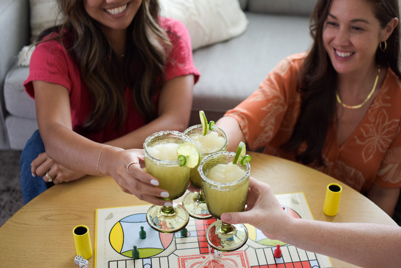 People enjoying D'Marie Spicy Margarita Slush Mix pouch featuring bold jalapeño and lime design, craft cocktail mix to blend with tequila and freeze. Available at Be Charmed