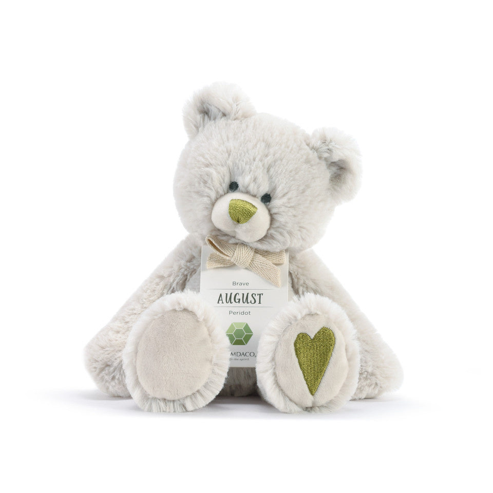 A plush teddy bear with a birthstone theme, featuring a ribbon around its neck that indicates the month of August Available at Be Charmed
