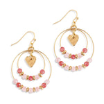Gold hoop earrings with pink beads and heart charms on a white background. Available at Be Charmed