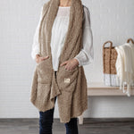 Demdaco Giving Shawl in camel (27″×70″), buttery‑soft fabric with two pockets—giftable hug, available at Be Charmed.