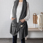 Demdaco Giving Shawl in charcoal (27″×70″), buttery‑soft fabric with two pockets—giftable hug, available at Be Charmed.