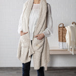 Demdaco Giving Shawl in cream (27″×70″), buttery‑soft fabric with two pockets—giftable hug, available at Be Charmed.