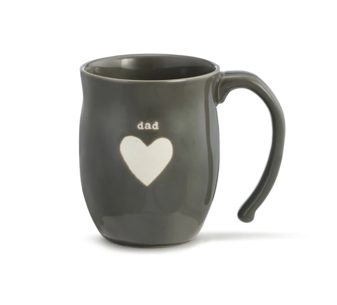 A gray ceramic mug with the word 'dad' written on it and a heart shape below. The mug appears to be made from stoneware. Availabe at Be Charmed