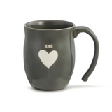 A gray ceramic mug with the word 'dad' written on it and a heart shape below. The mug appears to be made from stoneware. Availabe at Be Charmed