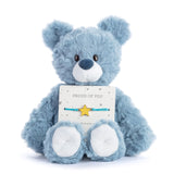 Blue teddy bear holding a 'Proud of You' card with a star bracelet on a white background. Available at Be Charmed