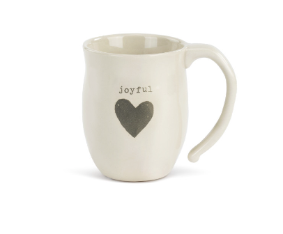 A beige ceramic mug with a heart shape design and the word 'joyful' printed on the side. Available at Be Charmed