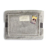 Gray lap blanket with a label and tag on a white background. Available at Be Charmed