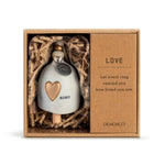 Ceramic Demdaco Love Mini Inspired Bell (~2″×2.5″) pictured in box; with hanging cord and wood bead—uplifting decor with inspirational message. Available at Be Charmed.