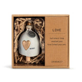 Ceramic Demdaco Love Mini Inspired Bell (~2″×2.5″) pictured in box; with hanging cord and wood bead—uplifting decor with inspirational message. Available at Be Charmed.