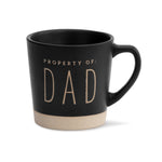 A black ceramic mug with the words 'PROPERTY OF: DAD' printed in capital letters on the side. The mug has a matte finish with a unglazed bottom. Available at Be Charmed