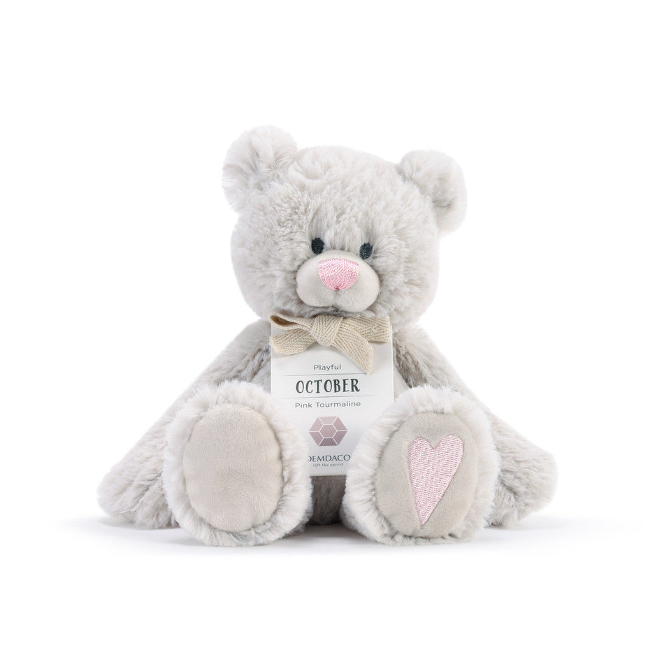 A plush teddy bear with a birthstone theme, featuring a ribbon around its neck that indicates the month of October. Available at Be Charmed