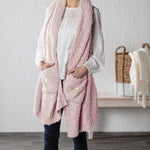 Demdaco Giving Shawl in pink (27″×70″), buttery‑soft fabric with two pockets—giftable hug, available at Be Charmed.