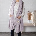 Demdaco Giving Shawl in purple (27″×70″), buttery‑soft fabric with two pockets—giftable hug, available at Be Charmed.
