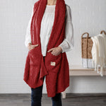 Demdaco Giving Shawl in red (27″×70″), buttery‑soft fabric with two pockets—giftable hug, available at Be Charmed.