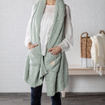 Demdaco Giving Shawl in sage (27″×70″), buttery‑soft fabric with two pockets—giftable hug, available at Be Charmed.