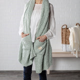 Demdaco Giving Shawl in sage (27″×70″), buttery‑soft fabric with two pockets—giftable hug, available at Be Charmed.