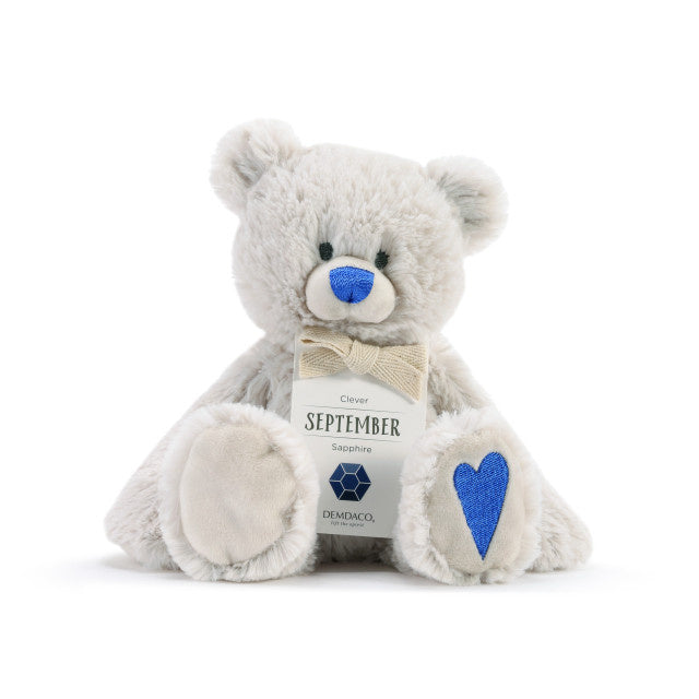 A plush teddy bear with a birthstone theme, featuring a ribbon around its neck that indicates the month of September. Avaiable at Be Charmed.